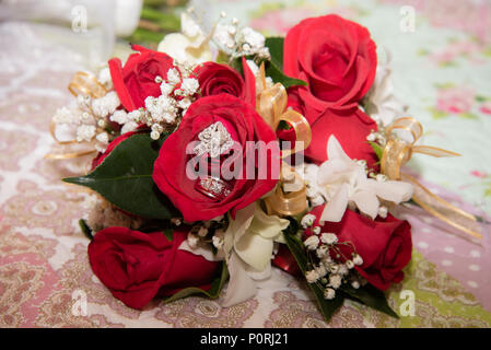 Belle photo aux couleurs avec les anneaux de mariage de diamant située au-dessus d'un bouquet de roses rouges Banque D'Images