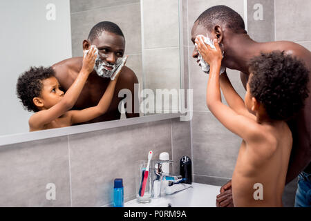 Adorable fils africains-américains l'application de la mousse sur le père Banque D'Images