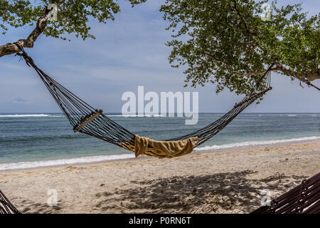 Un hamac et une serviette noire svinging entre deux arbres sur la plage tropicale, Trawngan Gili, Indonésie, le 25 avril, 2018 Banque D'Images