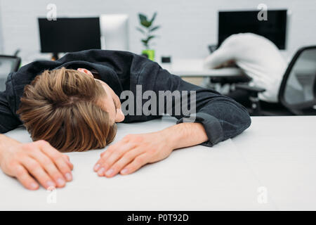 Les jeunes surchargés de travail à dormir sur le gestionnaire de bureau moderne Banque D'Images