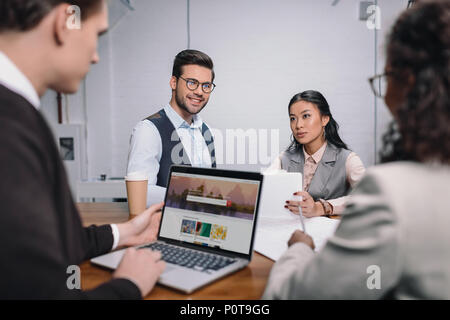 L'équipe entreprises multiethnique avec des documents et ordinateur portable avec shutterstock website Banque D'Images