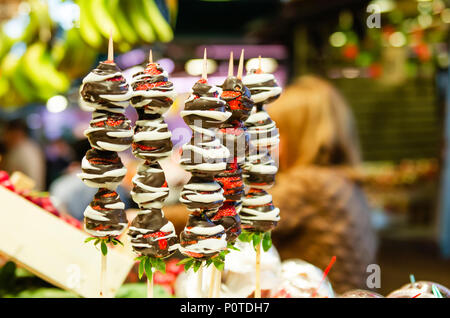 Fraises fraîches enrobées de chocolat. La fraise au chocolat sur une baguette de bois sur une étagère du marché Banque D'Images