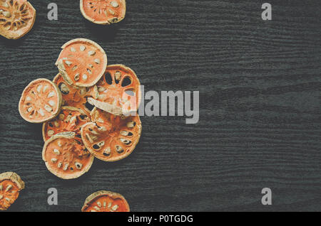 Les herbes séchées et séchées fruit de bael, vue de dessus de bael sec sur le plancher en bois, des tranches de fruit de bael pour faire du jus bael sur le sombre tableau. Banque D'Images