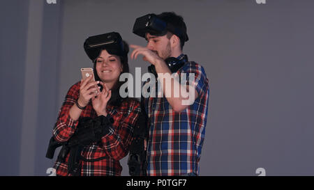 Couple de rire en réalité virtuelle à leurs casques à funny photos sur le téléphone Banque D'Images