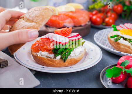 Du pain avec du fromage, radis, le saumon et les asperges, dans a woman's hand. Divers L'alimentation saine. Délicieux petit déjeuner pour la famille. La nourriture dans les Pays-Bas. Banque D'Images