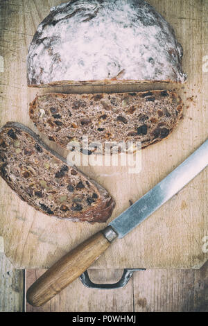 Pain au levain de fruits biologiques avec couteau à pain sur une planche de bois. UK. Vintage filtre appliqué Banque D'Images