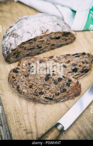 Pain au levain de fruits biologiques avec couteau à pain sur une planche de bois. UK. Vintage filtre appliqué Banque D'Images