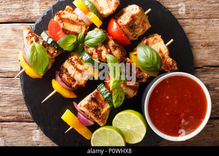 Brochettes de poulet grillé avec sauce aux légumes d'été, le basilic et lime gros plan sur la table. Haut horizontale Vue de dessus Banque D'Images