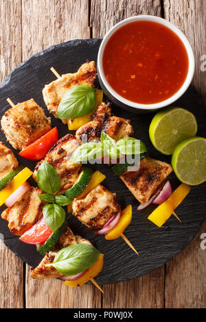 Brochettes de poulet grillé avec sauce aux légumes d'été, le basilic et lime gros plan sur la table. Haut Vertical Vue de dessus Banque D'Images