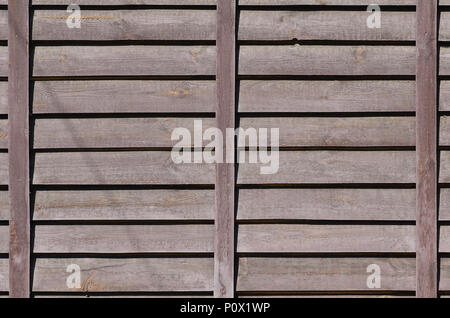 Texture horizontale d'un mur de plusieurs rangées de vieilles planches en bois brun. Mur en bois peint de couleur brune Banque D'Images