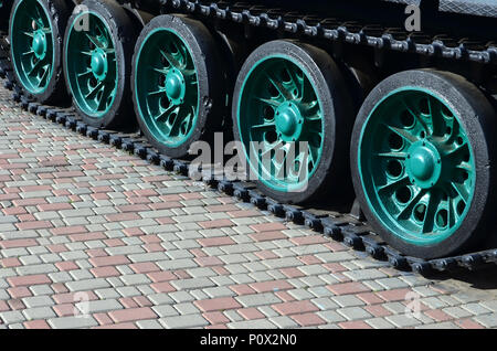 Un véhicule militaire sur chenilles se tient sur un carré de pavés. Photo de chenilles vertes avec des roues en métal que les faire tourner Banque D'Images