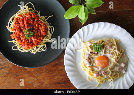 Spaghetti Carbonara avec d'œuf et les pâtes italiennes spaghetti avec sauce tomate sur table en bois Banque D'Images
