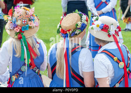 Trois danseurs morris femelle portant des chapeaux d'été couverte de fleurs colorées et ruban chat lors d'un événement de danse dans le West Sussex, Angleterre, Royaume-Uni. Banque D'Images