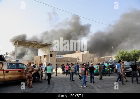 Bagdad, Iraq. 10 Juin, 2018. Les forces de sécurité irakiennes et les pompiers rassembler comme des ondes de fumée dans des entrepôts à Bagdad, l'Iraq, le 10 juin 2018. Un violent incendie a éclaté dimanche dans trois entrepôts contenant des boîtes de scrutin de l'élection parlementaire au centre-ville de capitale Bagdad. Credit : Khalil Dawood/Xinhua/Alamy Live News Banque D'Images