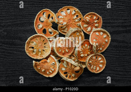 Les herbes séchées et séchées fruit de bael, vue de dessus de bael sec sur le plancher en bois, des tranches de fruit de bael pour faire du jus bael sur le sombre tableau. Banque D'Images