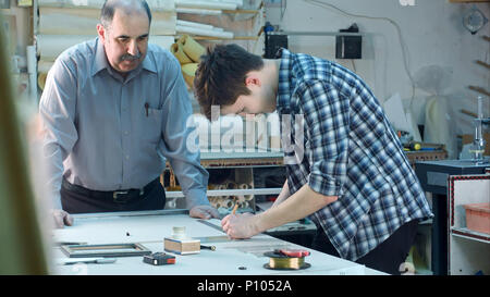 Jeune stagiaire de la construction d'un châssis derrière le bureau dans l'atelier du châssis Banque D'Images