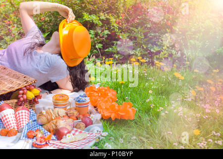 Fille avec un chapeau à un pique-nique, célébrant la journée du roi. Maison de vacances Orange. Tiempo de semaine. Manger sur l'herbe. Printemps et les fleurs aux Pays-Bas. Texte. Banque D'Images