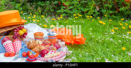 Pique-nique dans la célébration de la journée du roi. Déjeuner dans le jardin. Panier pour un pique-nique, de fruits et de pâtisseries. Chapeau Orange. Printemps dans les Pays-Bas. Carte postale et le texte. Banque D'Images