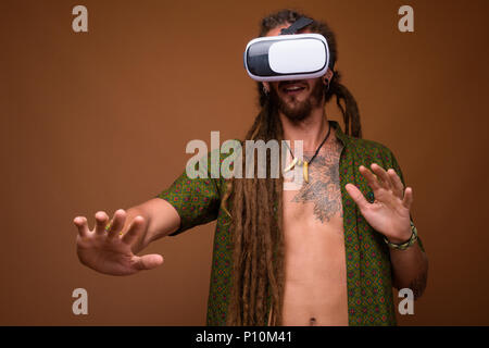 Beau jeune homme hispanique avec des dreadlocks contre brown zone Banque D'Images