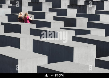 Deux femmes blondes avec les smartphones de prendre des photos dans le mémorial de l'Holocauste pour les Juifs assassinés à Berlin, Allemagne Banque D'Images