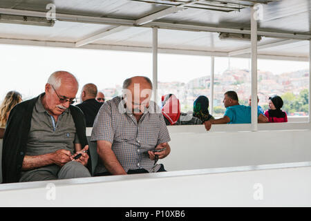 Istanbul, 17 juin 2017 : deux mâles adultes amis locaux sont flottant sur un ferry ou un bateau de passagers et d'utiliser les téléphones portables pour appeler ou application mobile Banque D'Images