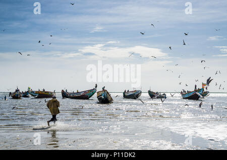 Pêcheur non identifiés en cours d'exécution dans l'eau pour bateau de pêche en bois peint traditionnel Banque D'Images
