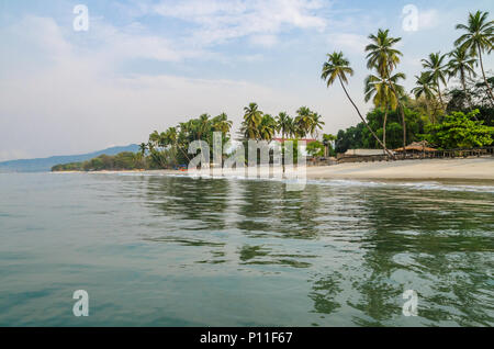 L'eau calme, palmiers et plage de sable blanc de Tokeh Beach, au sud de Freetown, Sierra Leone, Afrique Banque D'Images