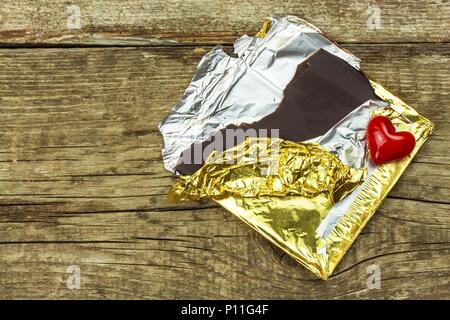 Chocolat amer dans une feuille d'or sur une planche de bois. La délicatesse du chocolat Banque D'Images