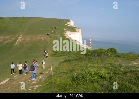 Fille de tourisme de prendre une photo et les touristes marcher près du bord des falaises et le phare de Beachy Head, Chalk pointe dans l'East Sussex, Angleterre Banque D'Images