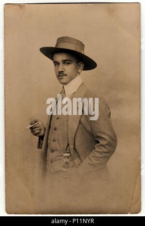 OLOMOUC, la République tchécoslovaque - VERS 1920 : Vintage photo montre homme dandy avec cigarette et hat. Photo noir blanc antique. Banque D'Images