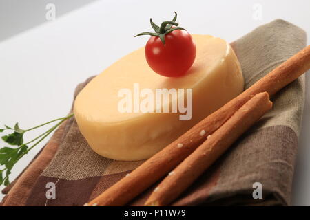 Petite meule de fromage à côté de tomates cerises Banque D'Images