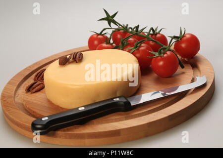 Petite meule de fromage à côté de tomates cerises Banque D'Images