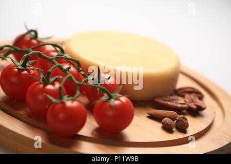 Petite meule de fromage à côté de tomates cerises Banque D'Images