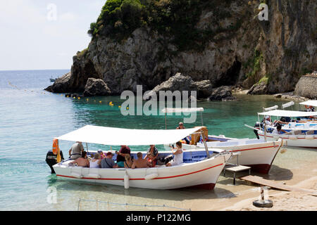 Paleokastritsa, Cofru, Grèce- 10 mai, 2018 grand groupe de personnes prennent une agréable randonnée sur un bateau motorisé. ride en face d'une colline avec des bouées Banque D'Images