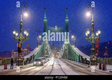 Voitures alignées à une lumière sur la neige couverts Pont de la liberté à Budapest Banque D'Images