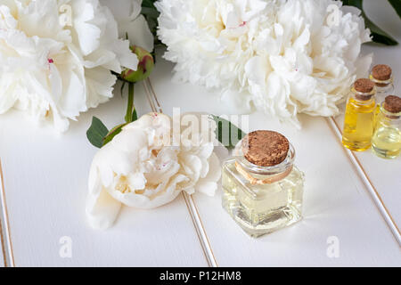 Une bouteille d'huile essentielle avec les fleurs blanches Banque D'Images
