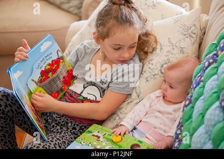 Fillette de six ans a lire à son bébé cousin Banque D'Images