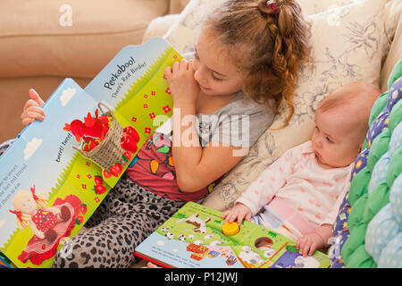 Fillette de six ans a lire à son bébé cousin Banque D'Images