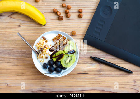 Design graphique et mode de vie sain concept, vue de dessus de tasse avec des bars et de raisins, kiwis à l'intérieur. Et tablette apple vert derrière sur l'onglet en bois Banque D'Images