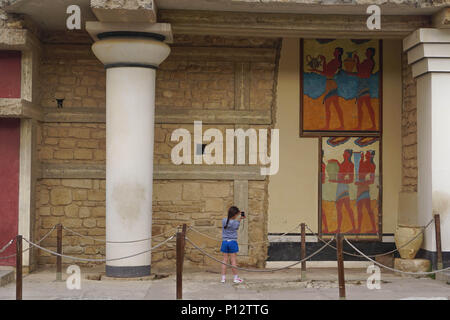 Knossos, Crète, Grèce : une petite fille s'arrête pour prendre une photo de l'art sur les murs de le palais minoen de Knossos. Banque D'Images