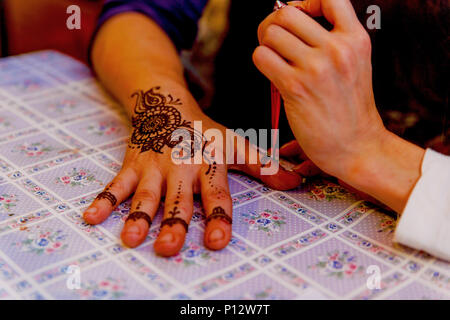 Mehendi henné peinture femme artiste sur la main. Banque D'Images