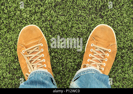 Dans l'homme chaussures en cuir et jeans se dresse sur l'herbe verte fraîche, vue du dessus Banque D'Images