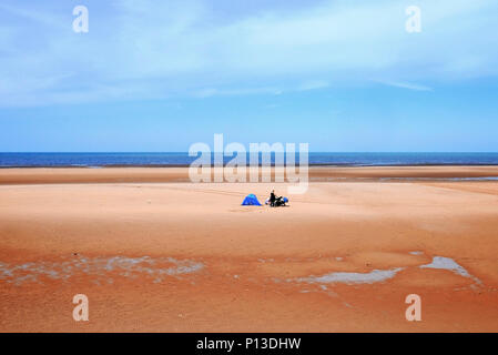 Famille solitaire avec blue tente sur une plage vide sur une journée chaude en été Banque D'Images