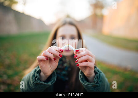 Cesser de fumer. Libre de Beautiful Girl Holding Broken cigarette dans les mains. Portrait Of Smiling Young Woman Breaking cigarette dans la moitié, cesser de SMO Banque D'Images