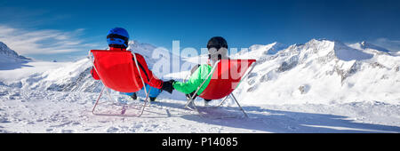 Jeune couple assis sur des transats et bénéficiant de superbes vue des Alpes, l'Europe. Banque D'Images