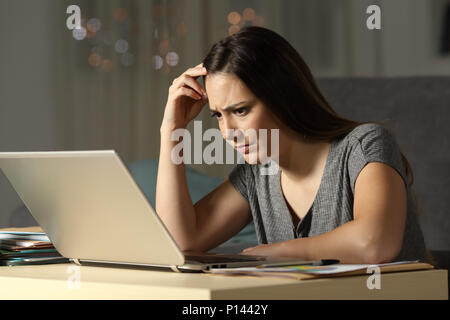 Confus femme travaillant à des heures tardives en ligne dans la nuit à la maison Banque D'Images