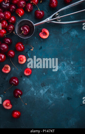 Les cerises et la crème glacée cuillère sur un fond de béton gris, l'été des petits fruits concept avec copie espace. Faire un dessert télévision réside dans des tons de couleur neutre Banque D'Images