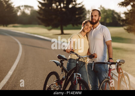 Couple heureux avec des bicyclettes à l'extérieur. Beau couple de cyclistes ayant reste sur la route de campagne. Dépenses passer du temps ensemble. Banque D'Images