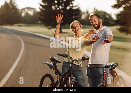 Heureux couple de cyclistes s'amusant à l'extérieur. Dans l'amour des gens mignons posant avec des vélos sur la route. L'amour, roman, de plaisir et de vie sain concept. Banque D'Images