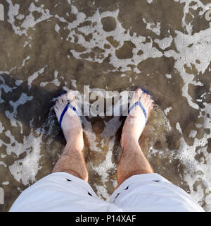 POV carré de style instagram coup de pieds dans l'océan avec des tongs Banque D'Images